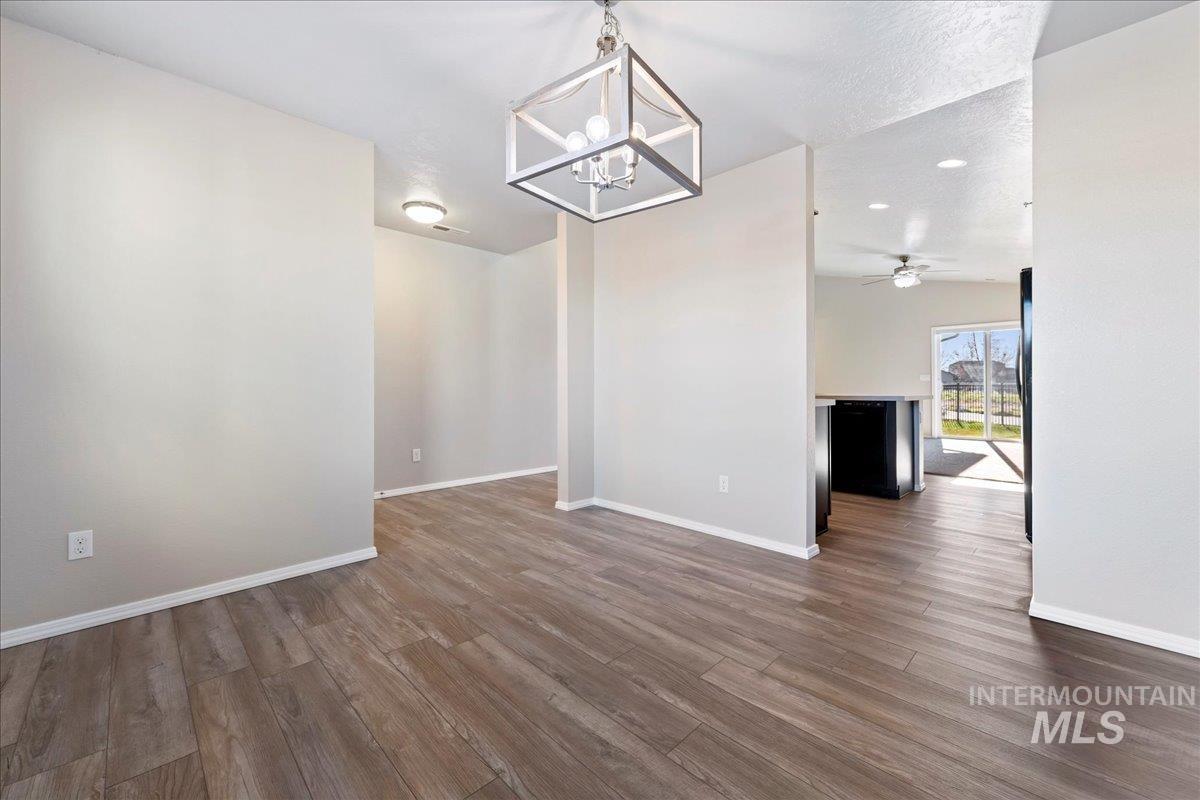 Unfurnished dining area featuring dark wood-type flooring, a chandelier, a ceiling fan, recessed lighting, and a textured ceiling