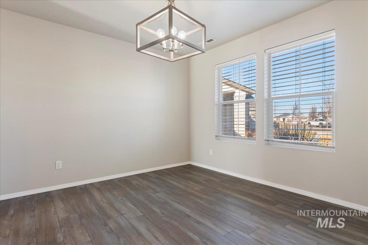 Spare room with dark wood-style flooring and a chandelier