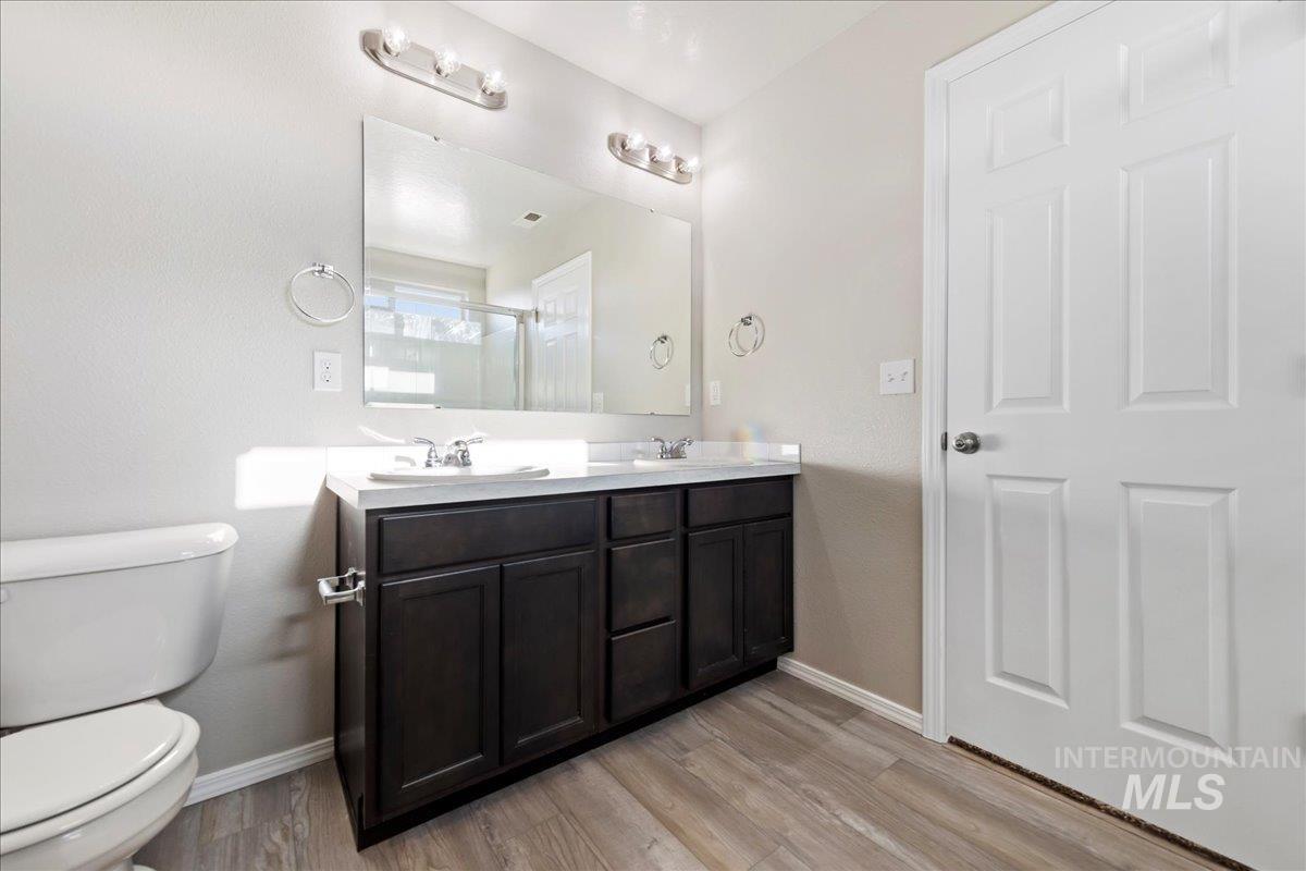 Bathroom with double vanity, light wood-style floors, and a shower stall