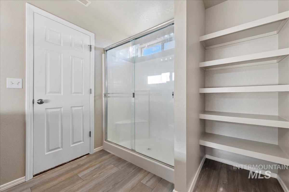 Full bath with wood finished floors and a shower stall