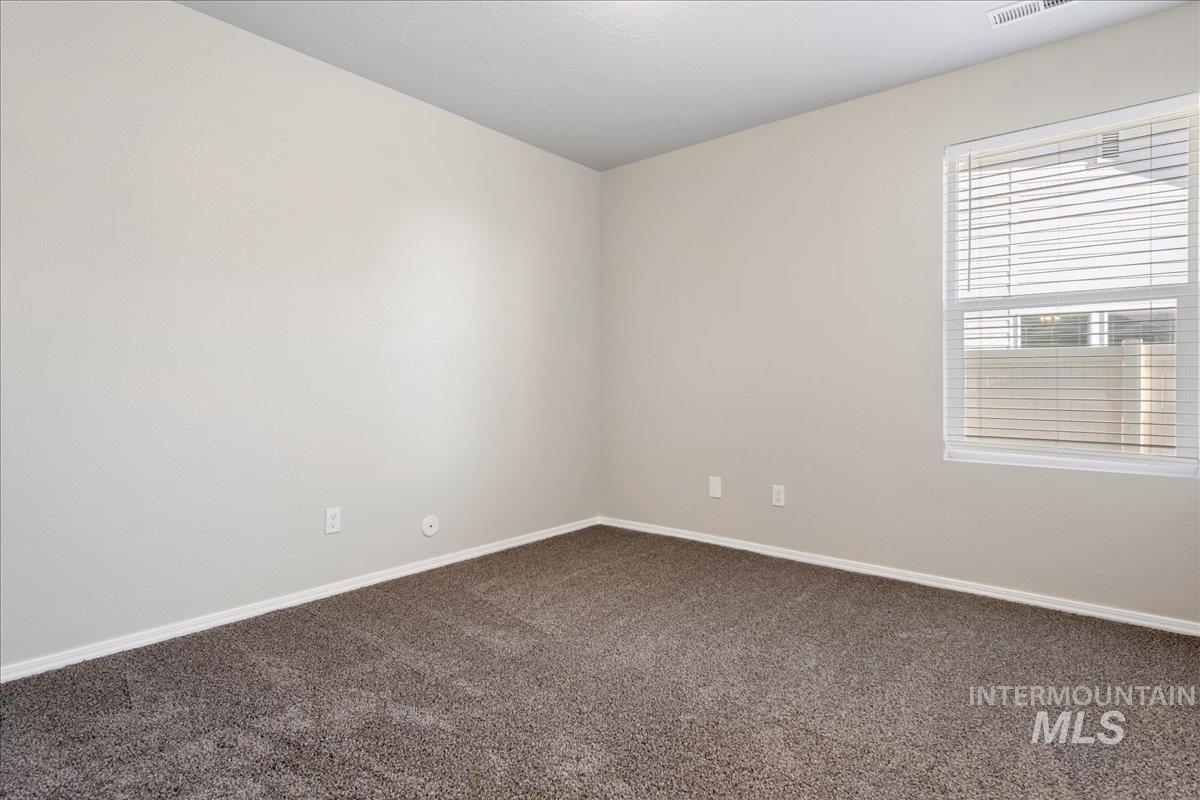 Unfurnished room featuring dark colored carpet and baseboards