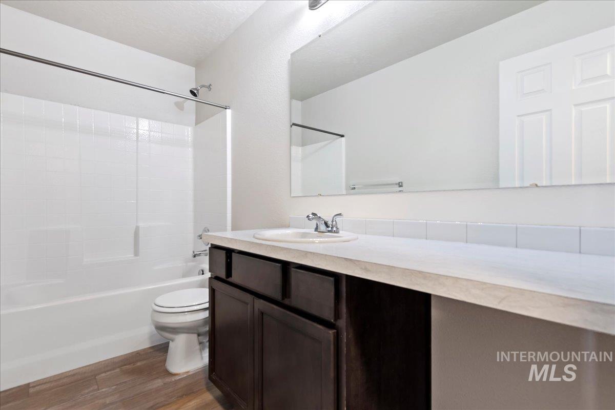 Full bathroom with tub / shower combination, vanity, and light wood finished floors