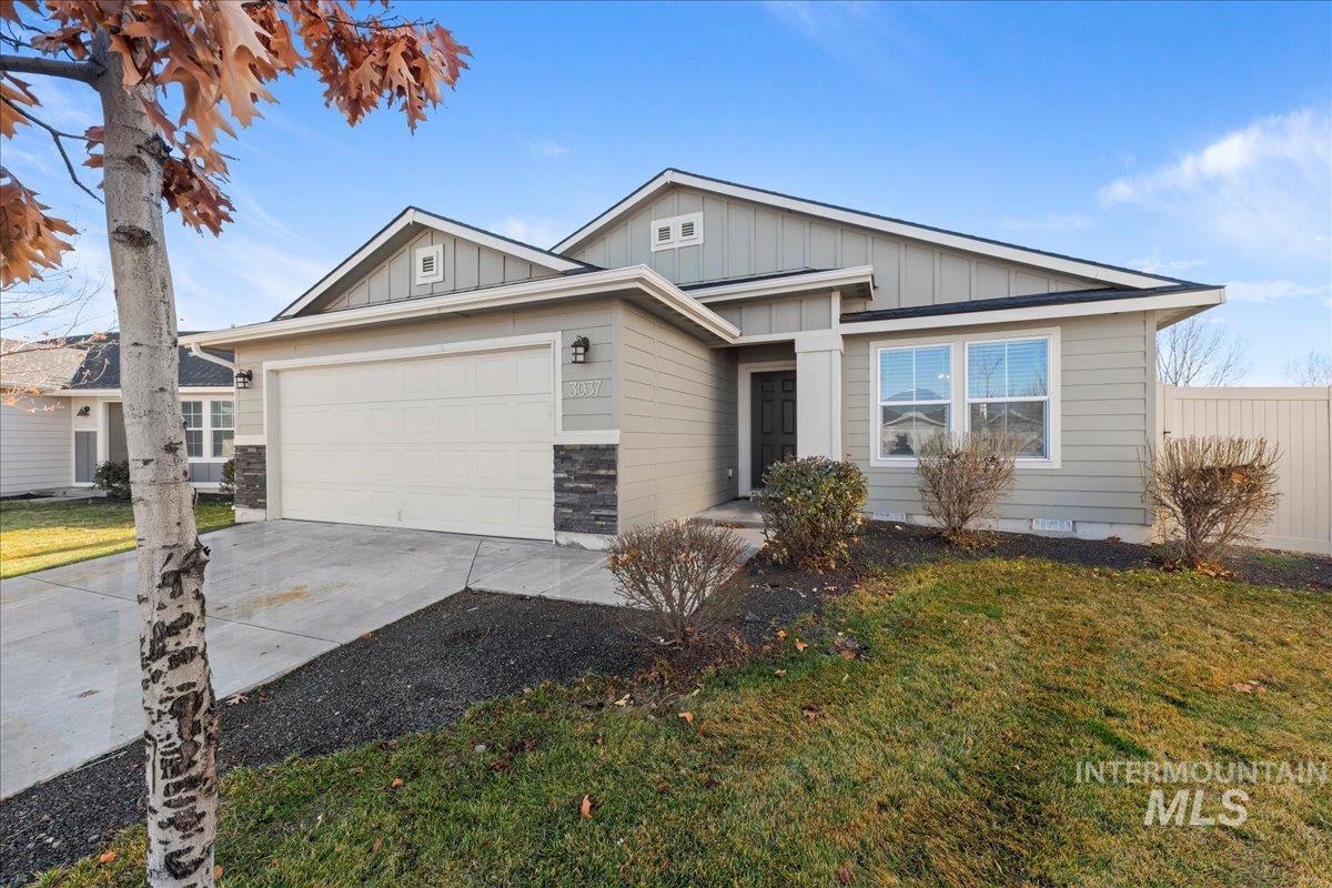 View of front of property with board and batten siding, concrete driveway, a front yard, and an attached garage