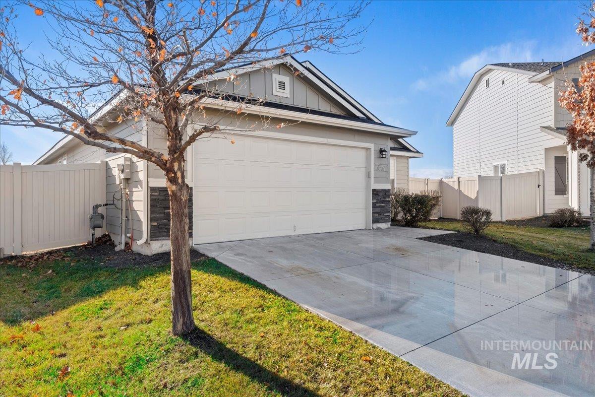 View of front facade with driveway, board and batten siding, and stone siding
