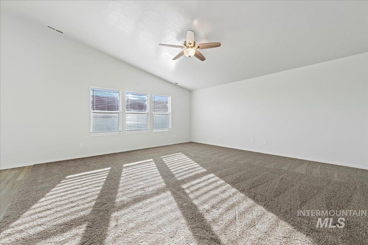 Spare room with lofted ceiling, carpet floors, and ceiling fan