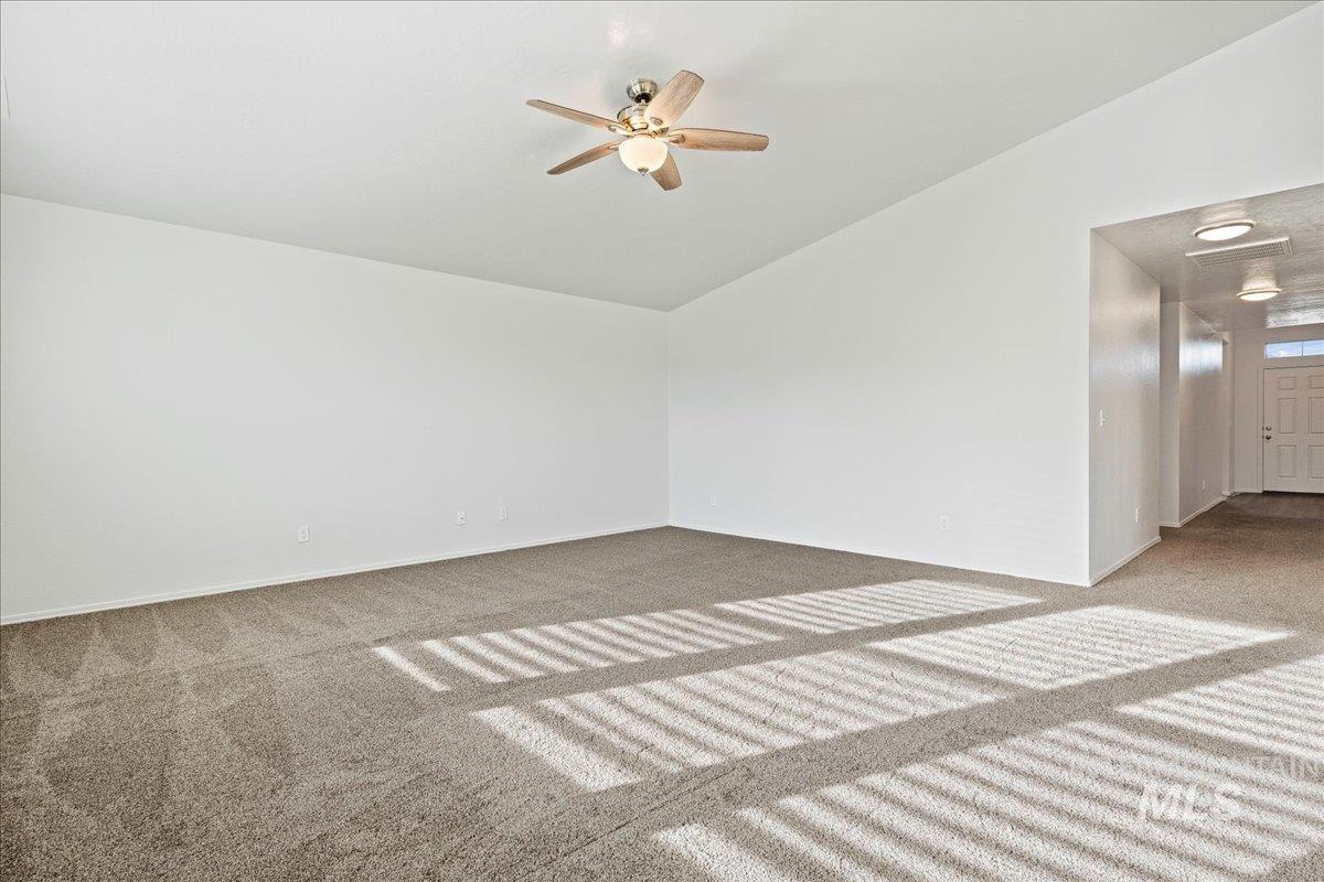 Spare room featuring carpet flooring, lofted ceiling, and ceiling fan