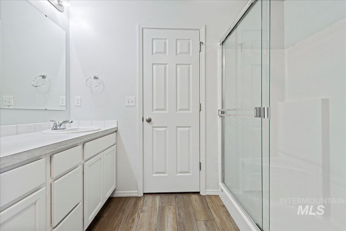 Bathroom with vanity, dark wood-type flooring, and a stall shower