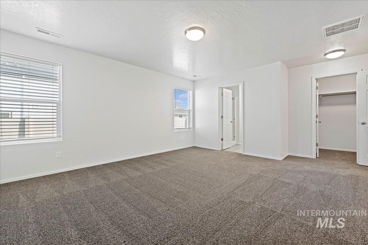 Unfurnished bedroom with a spacious closet, a textured ceiling, and carpet flooring