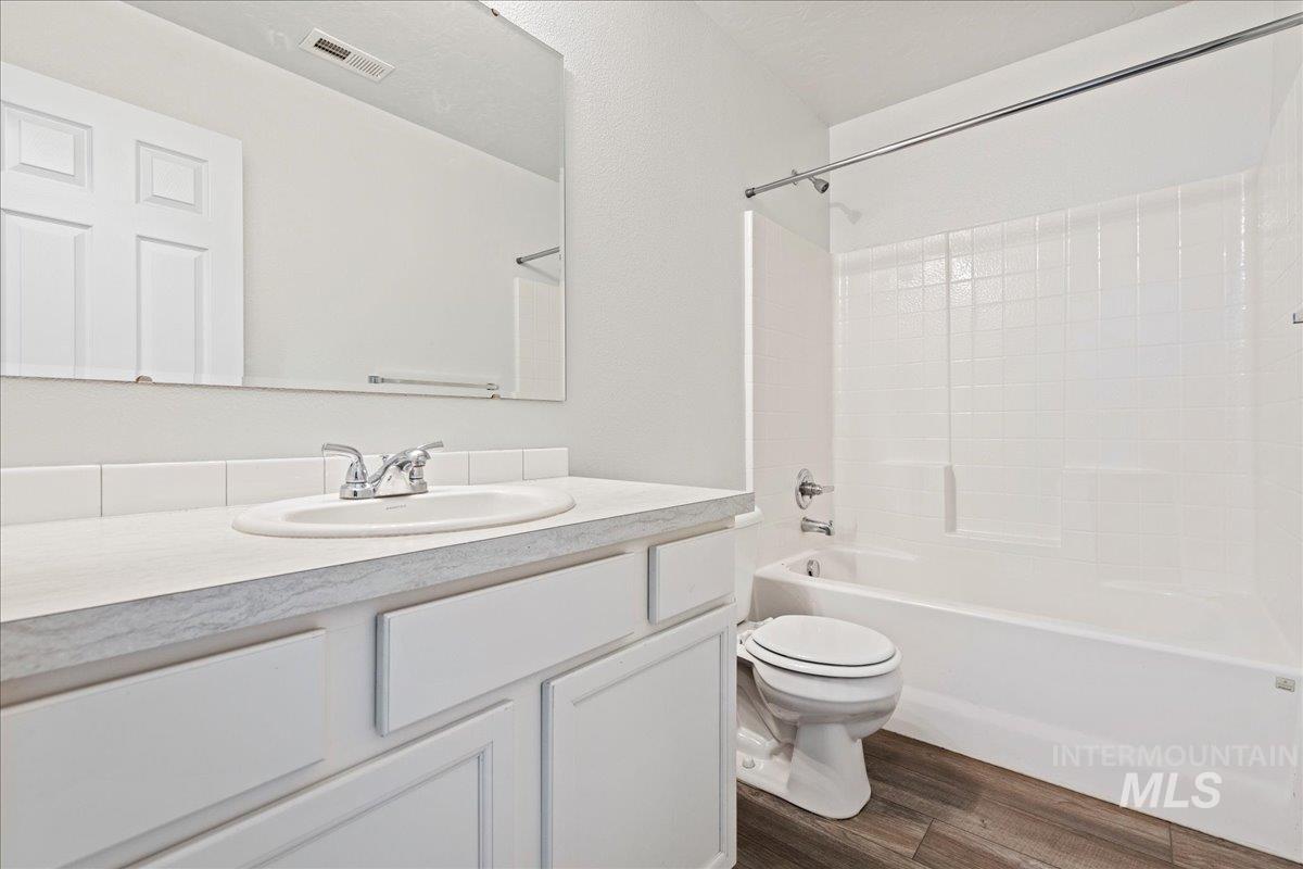 Full bath with shower / bathtub combination, vanity, and dark wood-style flooring