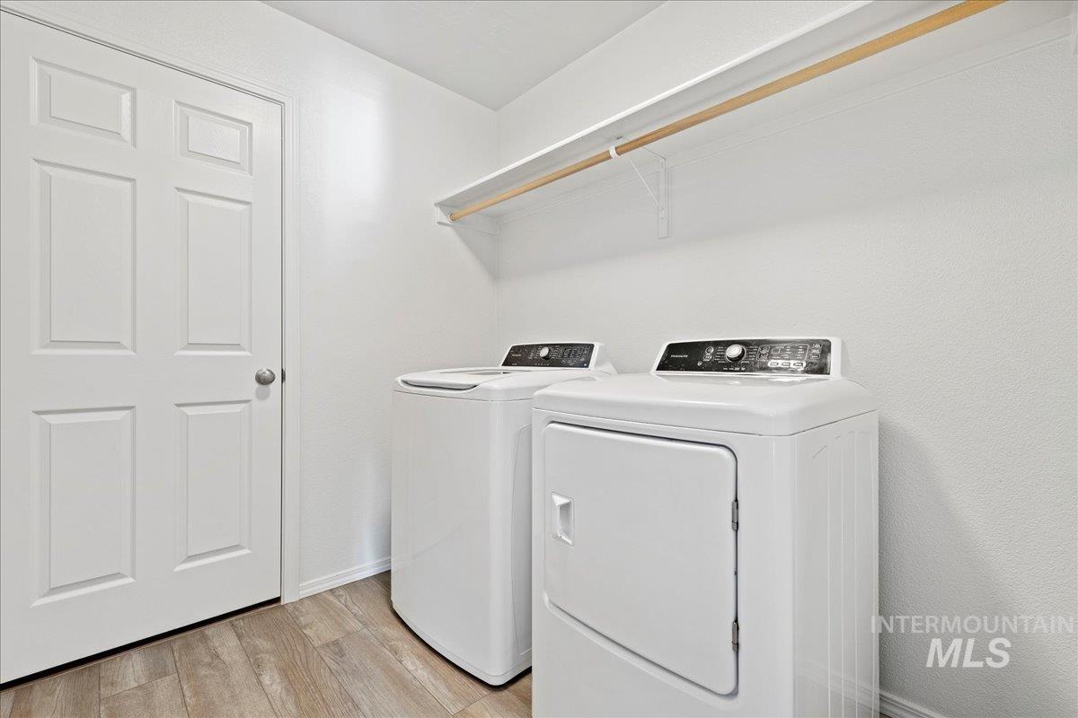 Laundry area featuring light wood finished floors and separate washer and dryer