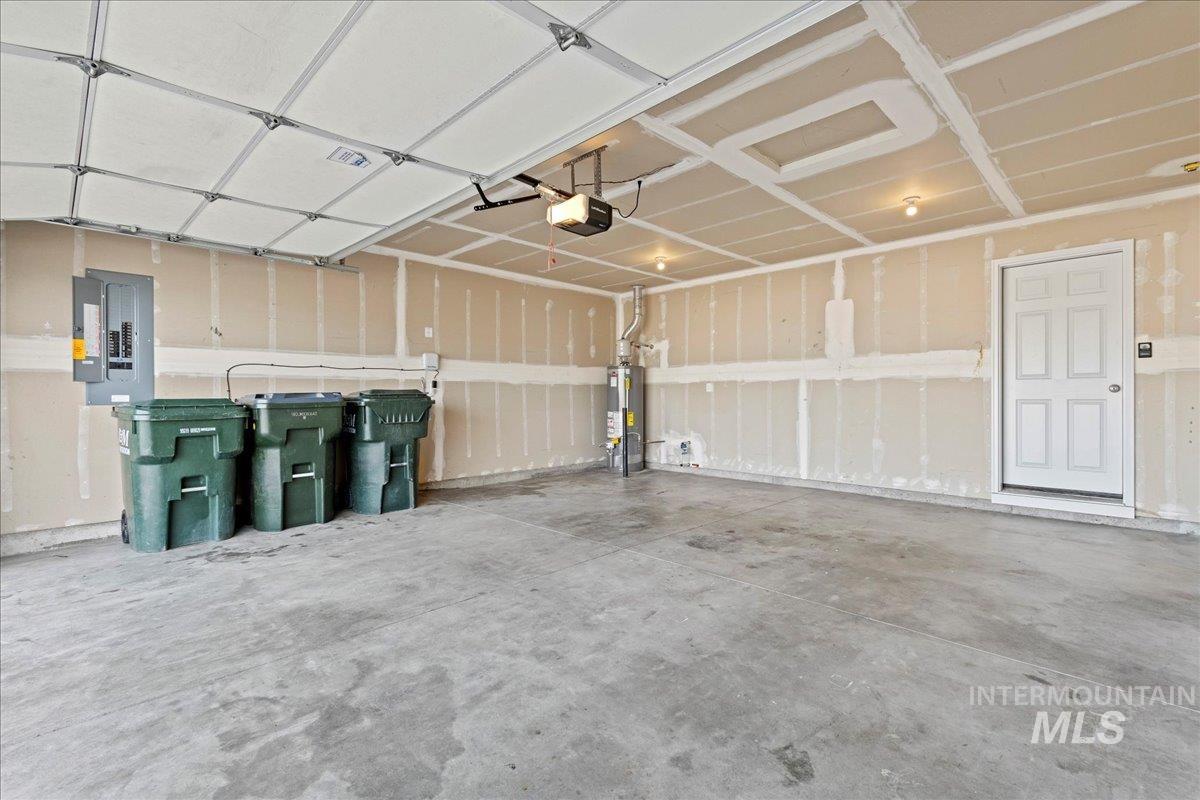 Garage featuring electric panel, gas water heater, and a garage door opener