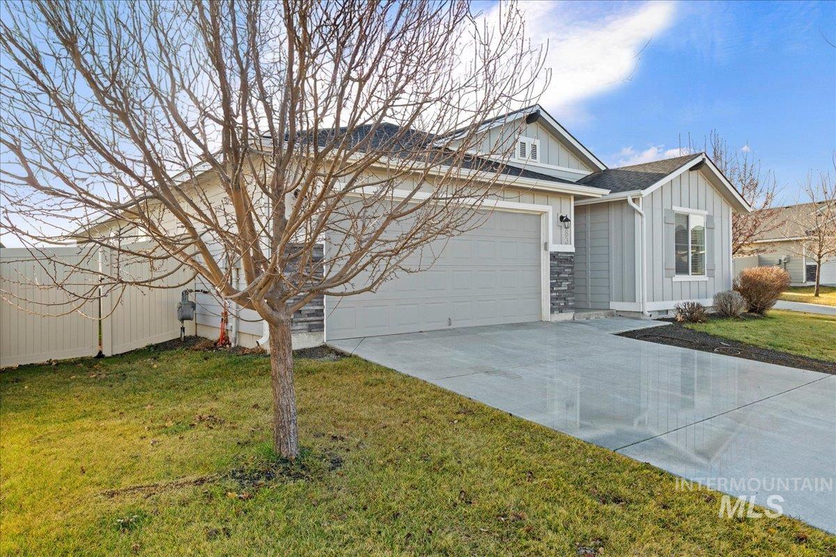 View of front facade with board and batten siding, concrete driveway, a front lawn, and a garage