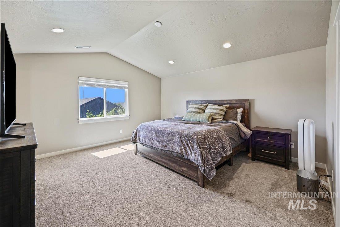 Bedroom featuring light carpet, a textured ceiling, lofted ceiling, and recessed lighting