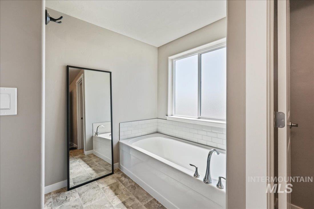 Full bathroom featuring a bath and baseboards
