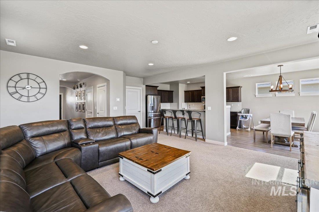 Living area with a textured ceiling, arched walkways, recessed lighting, a chandelier, and light colored carpet