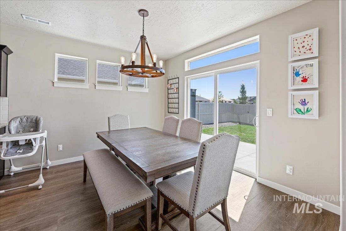 Dining area featuring a textured ceiling, dark wood-style flooring, and a chandelier