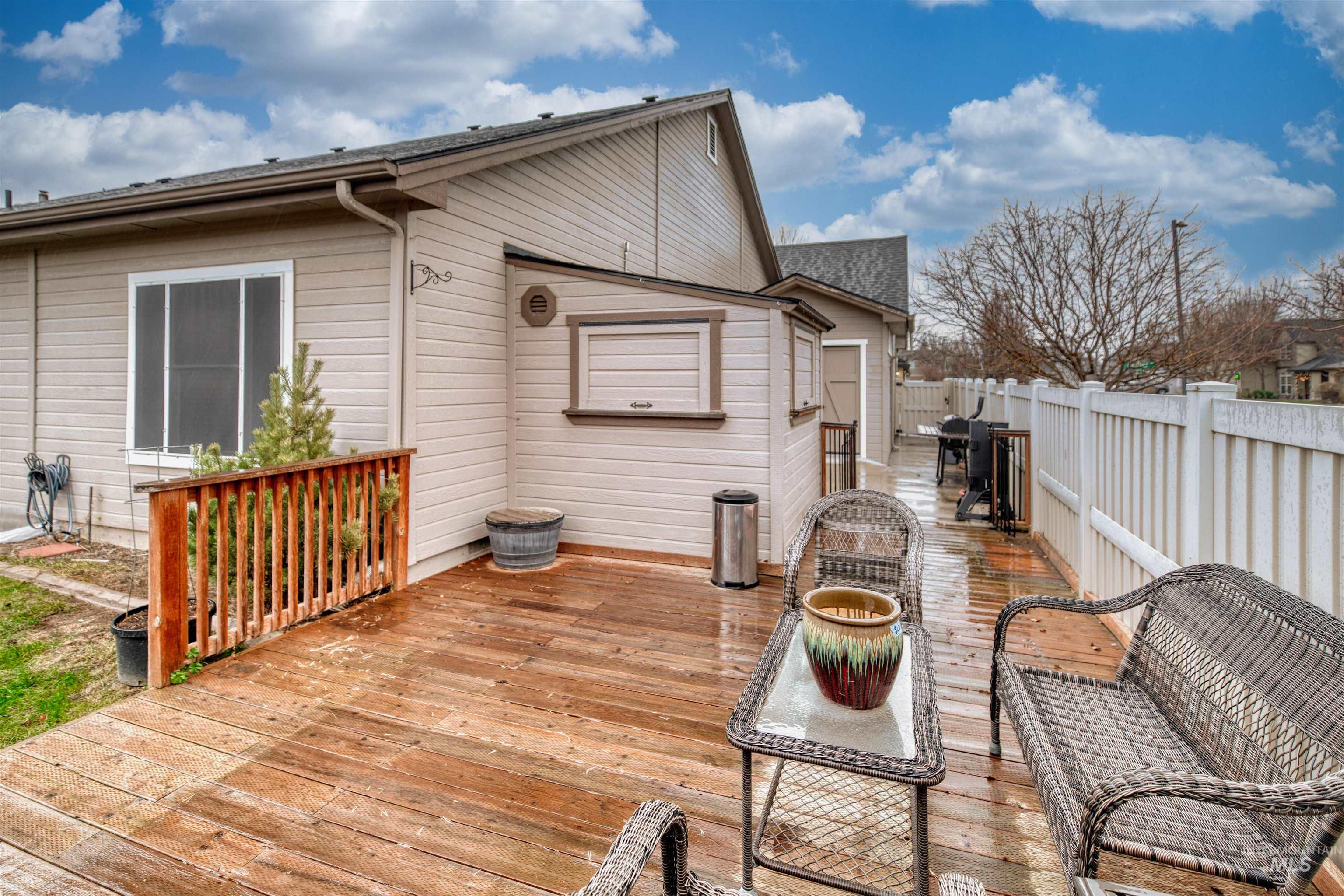 Wooden terrace with a fenced backyard and a grill