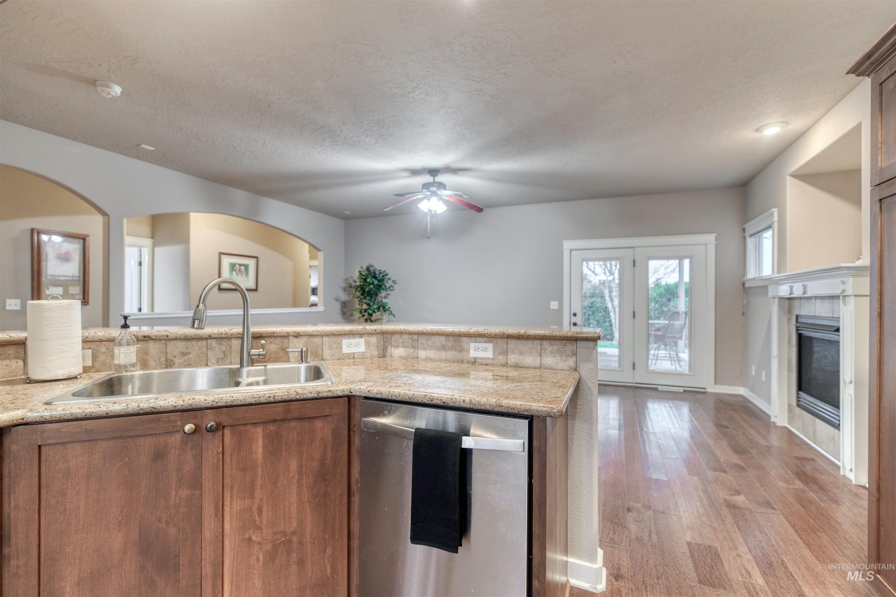 Kitchen with dishwasher, light wood-style flooring, a ceiling fan, open floor plan, and a textured ceiling