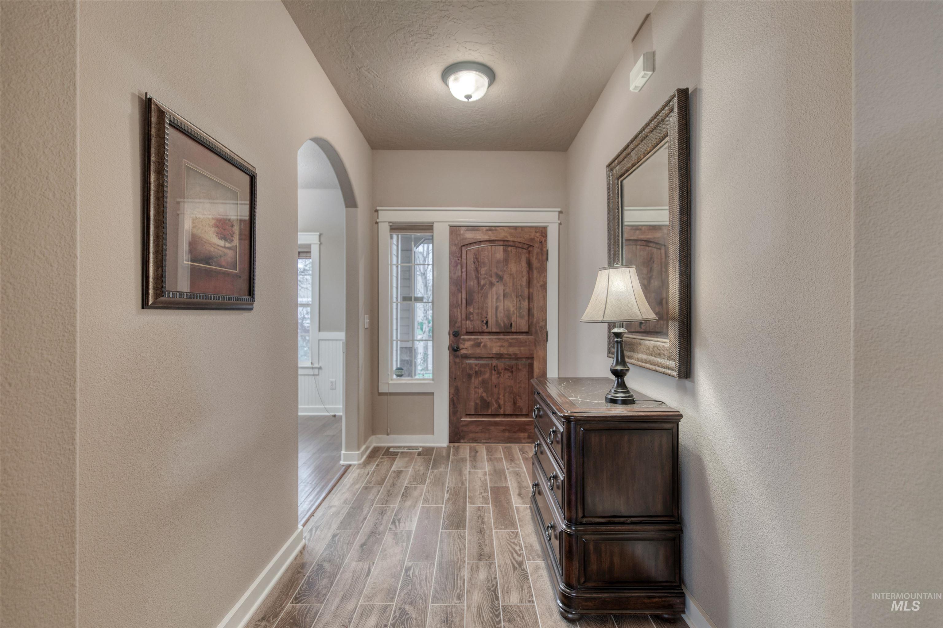 Foyer featuring wood tiled floors, a textured ceiling, a textured wall, and arched walkways