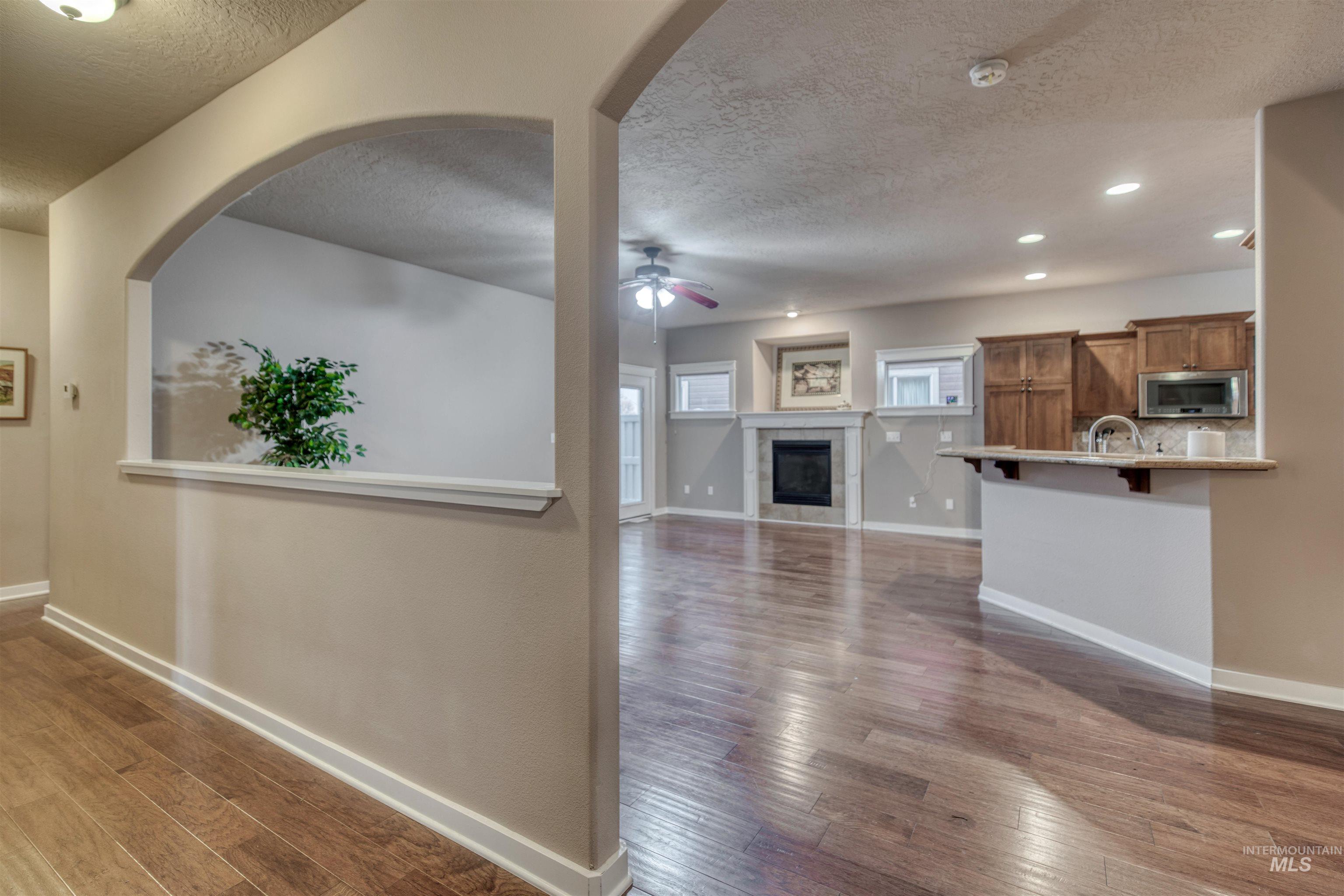 Unfurnished living room featuring a fireplace, a textured ceiling, dark wood-style flooring, recessed lighting, and a ceiling fan