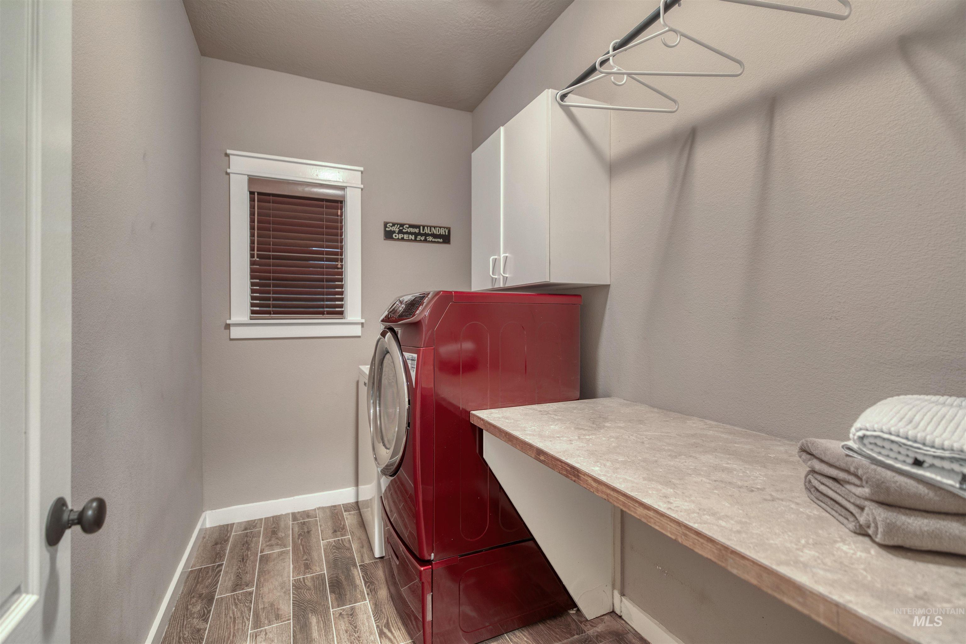 Washroom featuring wood tiled floors, cabinet space, and independent washer and dryer