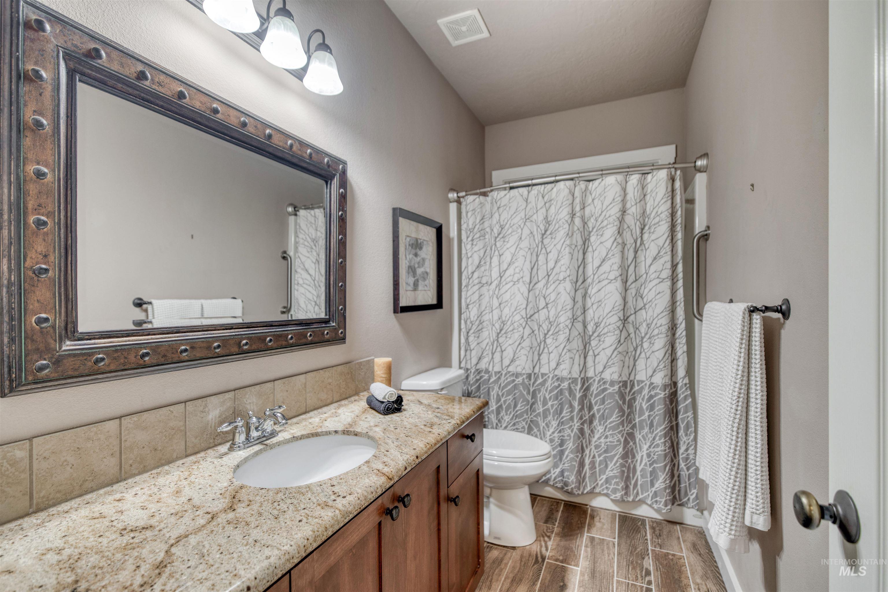 Full bath featuring wood tiled floors, vanity, and curtained shower