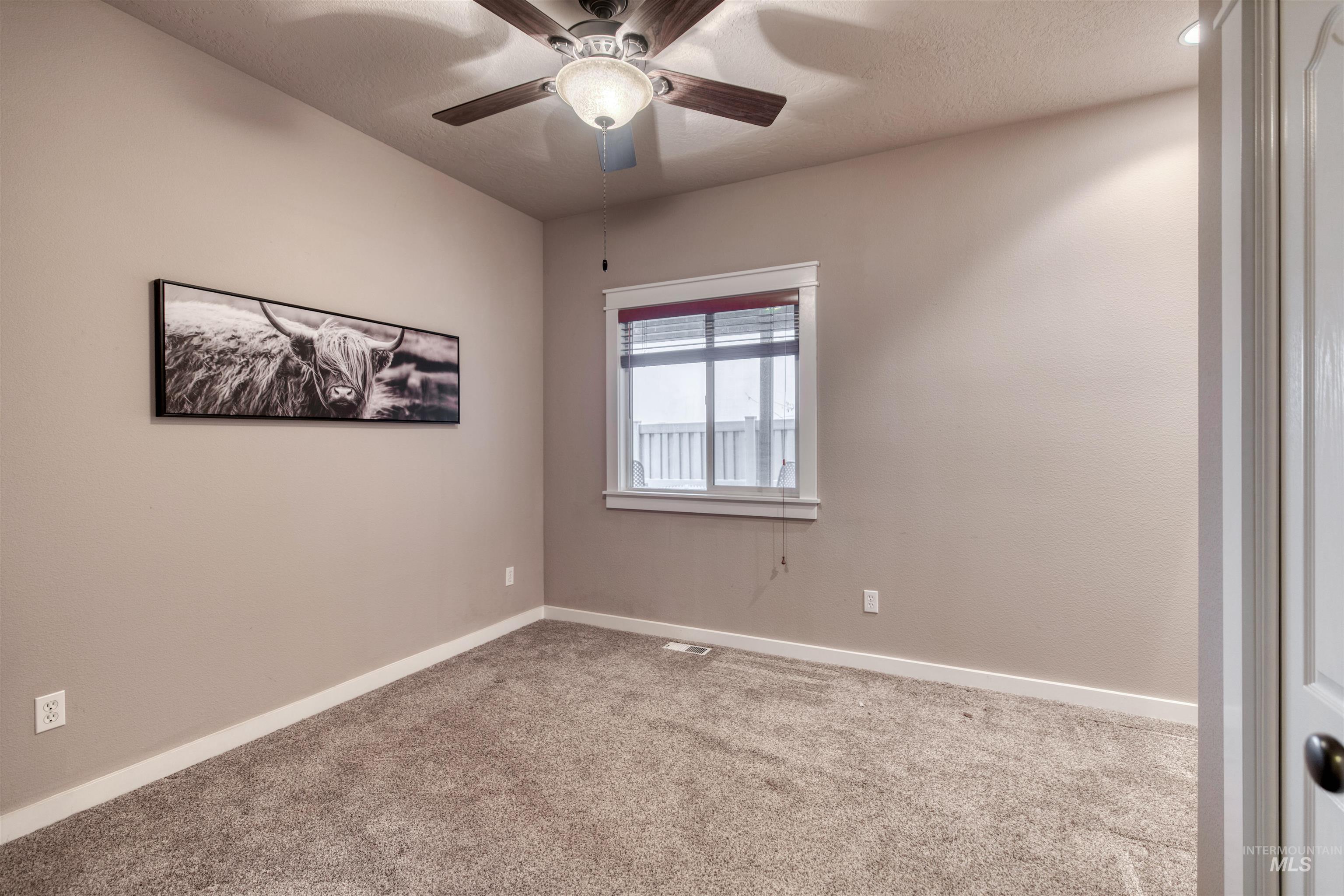Empty room featuring carpet floors, a textured ceiling, and a ceiling fan