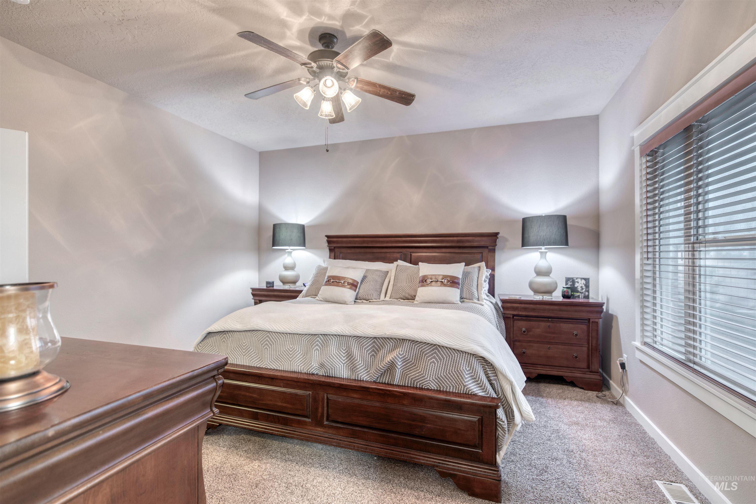 Bedroom featuring carpet floors, ceiling fan, and a textured ceiling