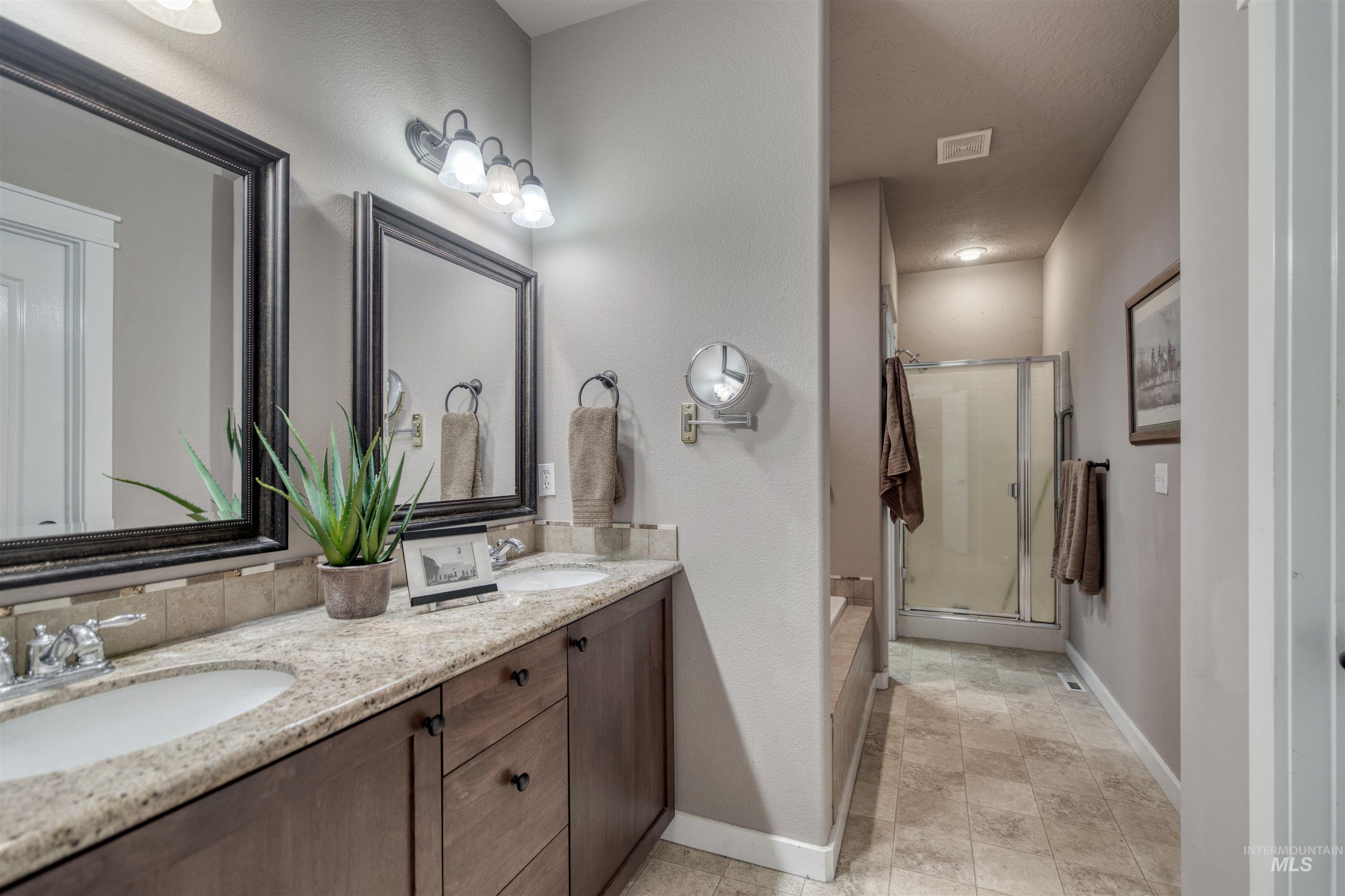 Full bath featuring a shower stall and double vanity