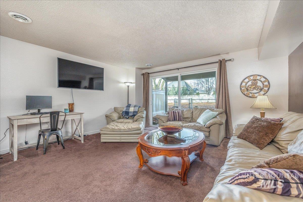 Living area with carpet flooring, a textured ceiling, and an office area