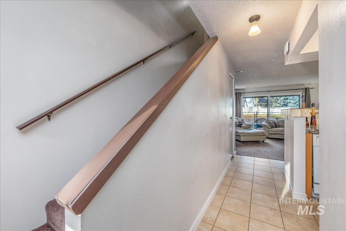 Corridor featuring a textured ceiling and light tile patterned flooring