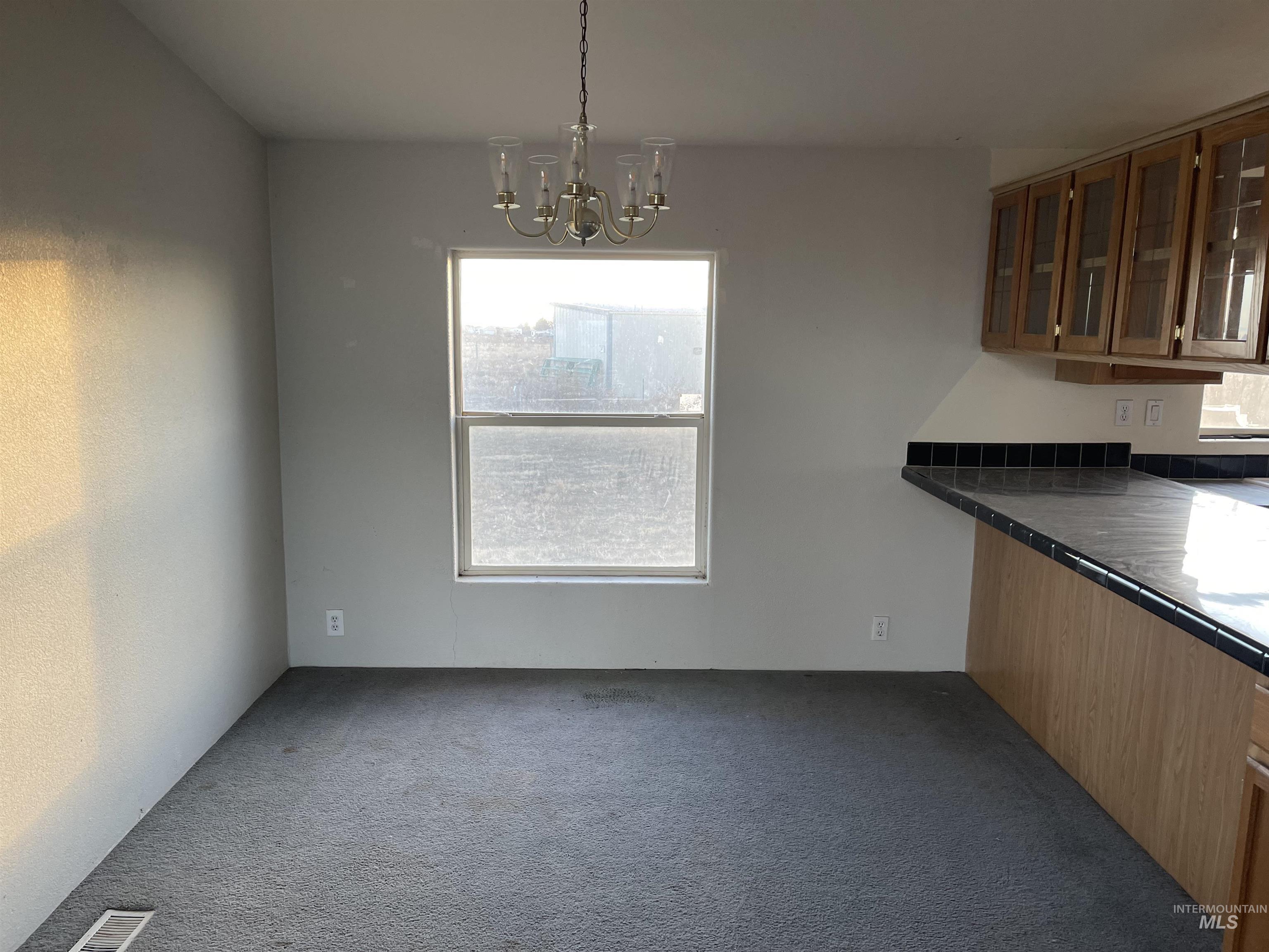 Unfurnished dining area featuring a chandelier and carpet floors