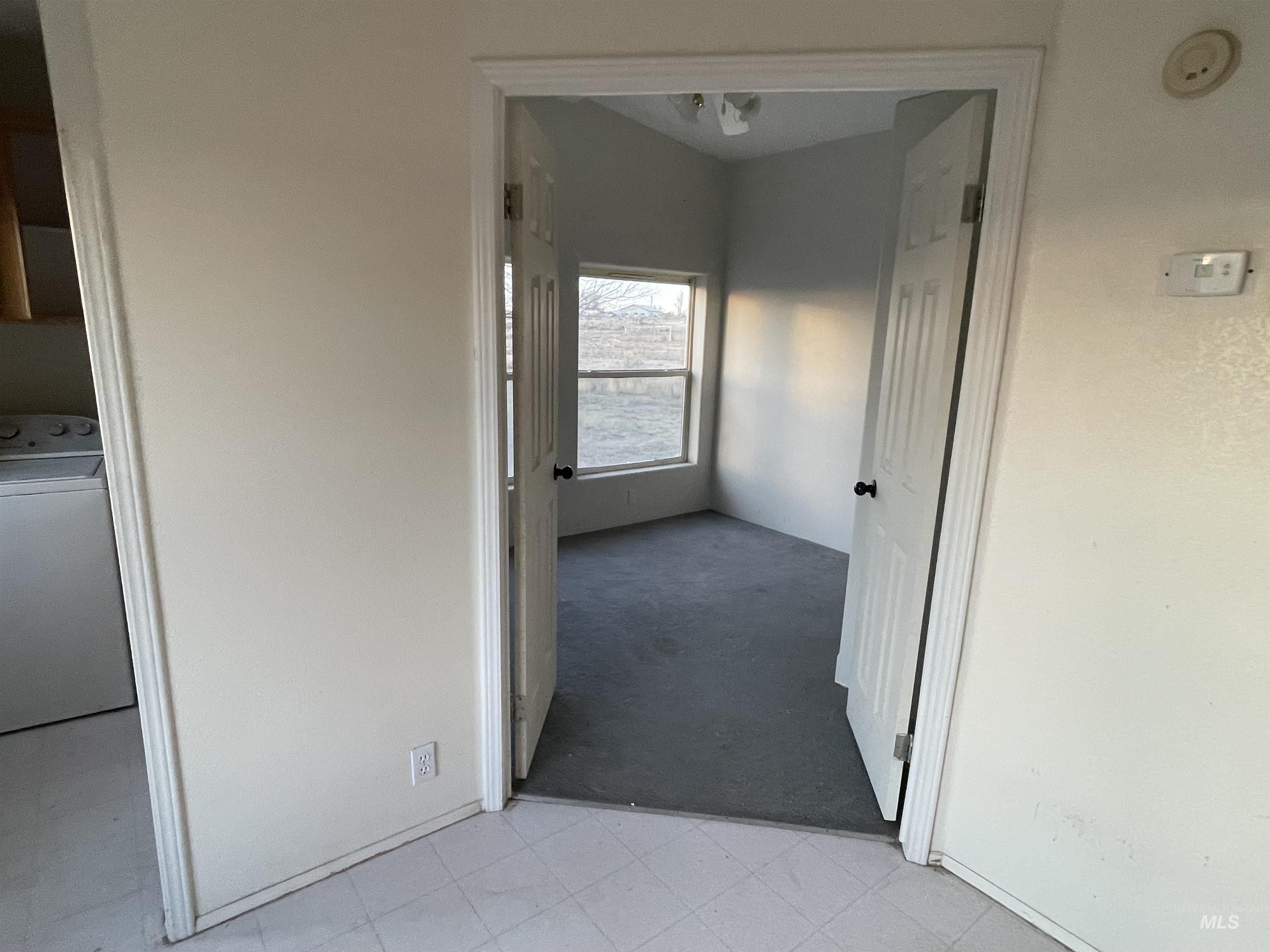 Hallway with washer / clothes dryer, light colored carpet, and light floors