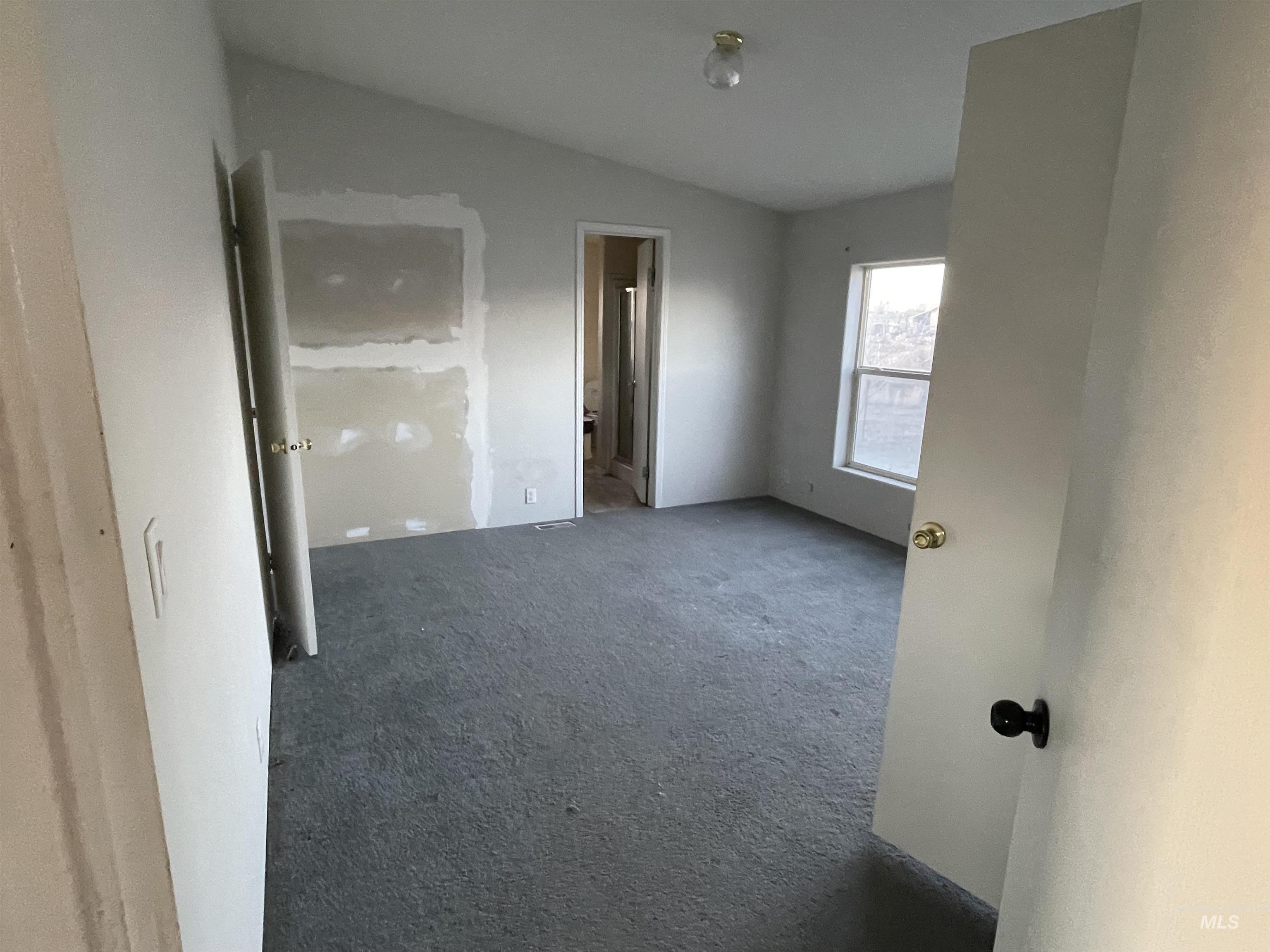 Unfurnished bedroom with carpet floors, vaulted ceiling, and connected bathroom