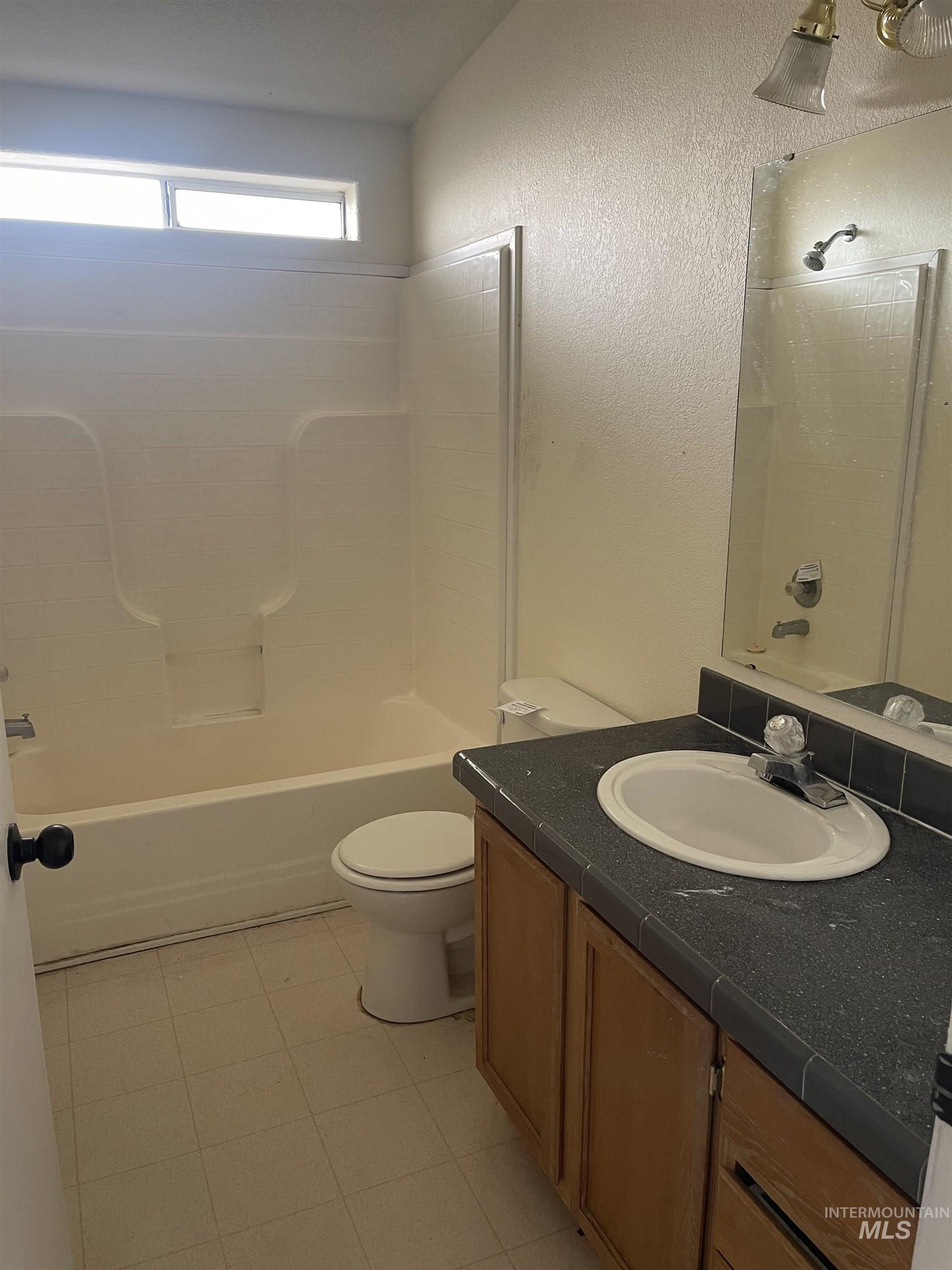 Full bath with vanity, shower / bathtub combination, and a textured wall