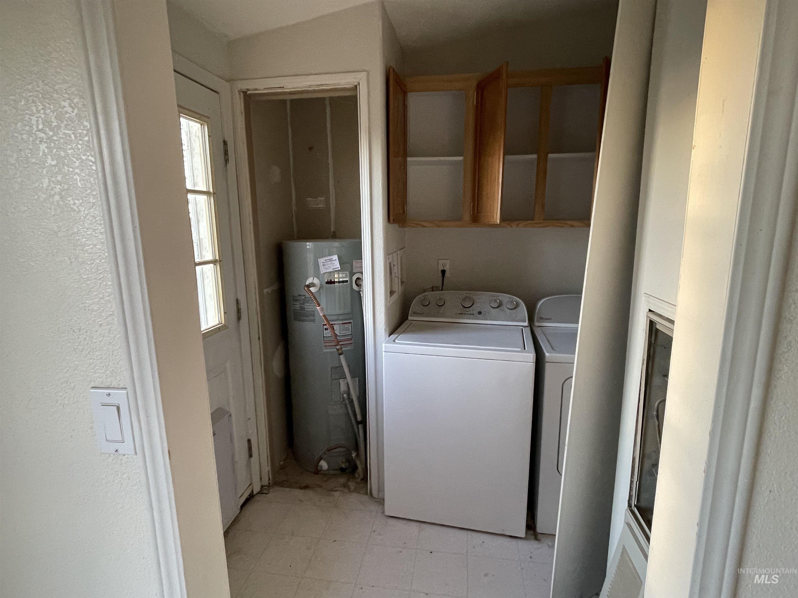 Washroom featuring light flooring, water heater, and washer and clothes dryer