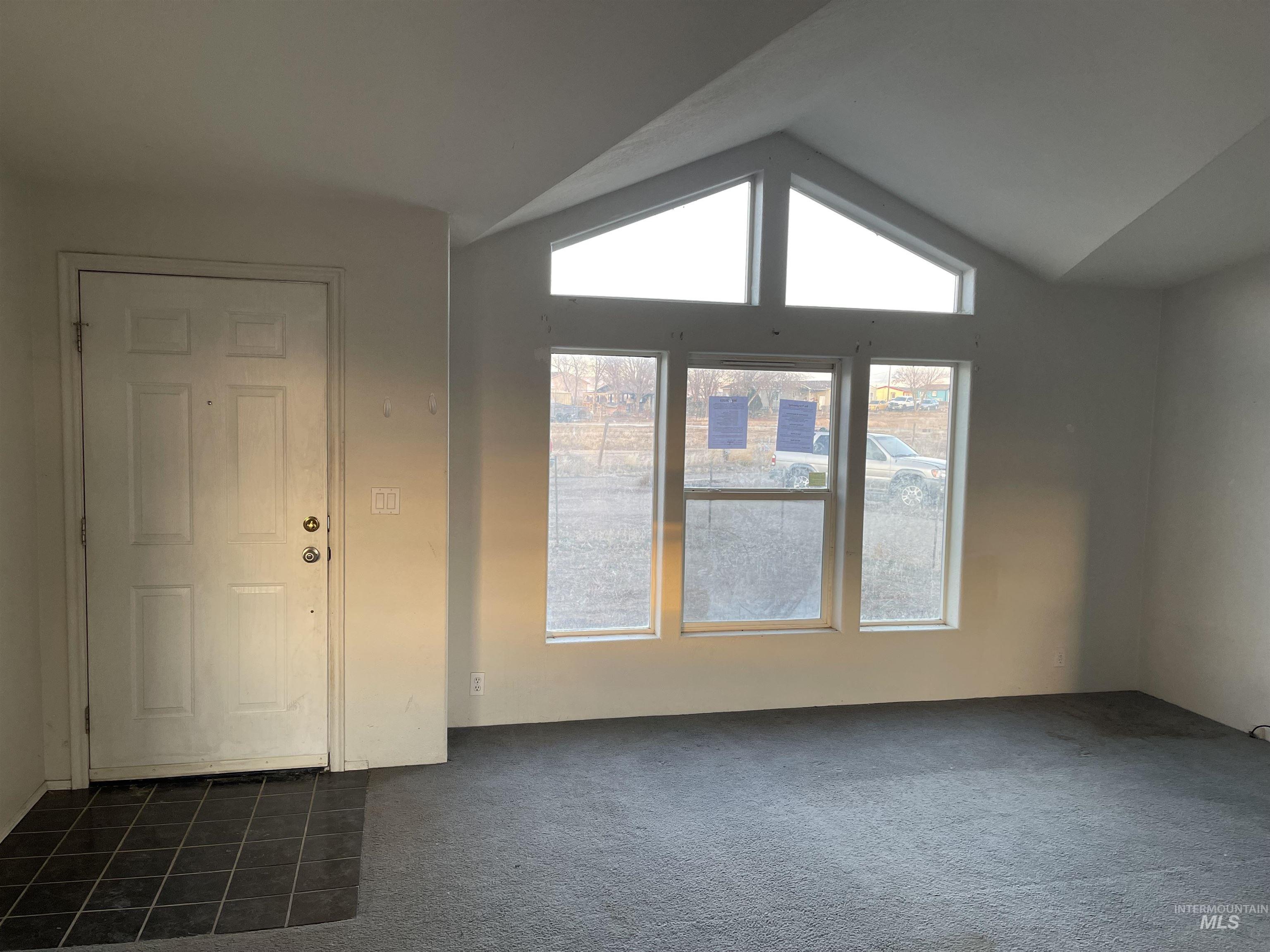 Foyer featuring vaulted ceiling and dark colored carpet