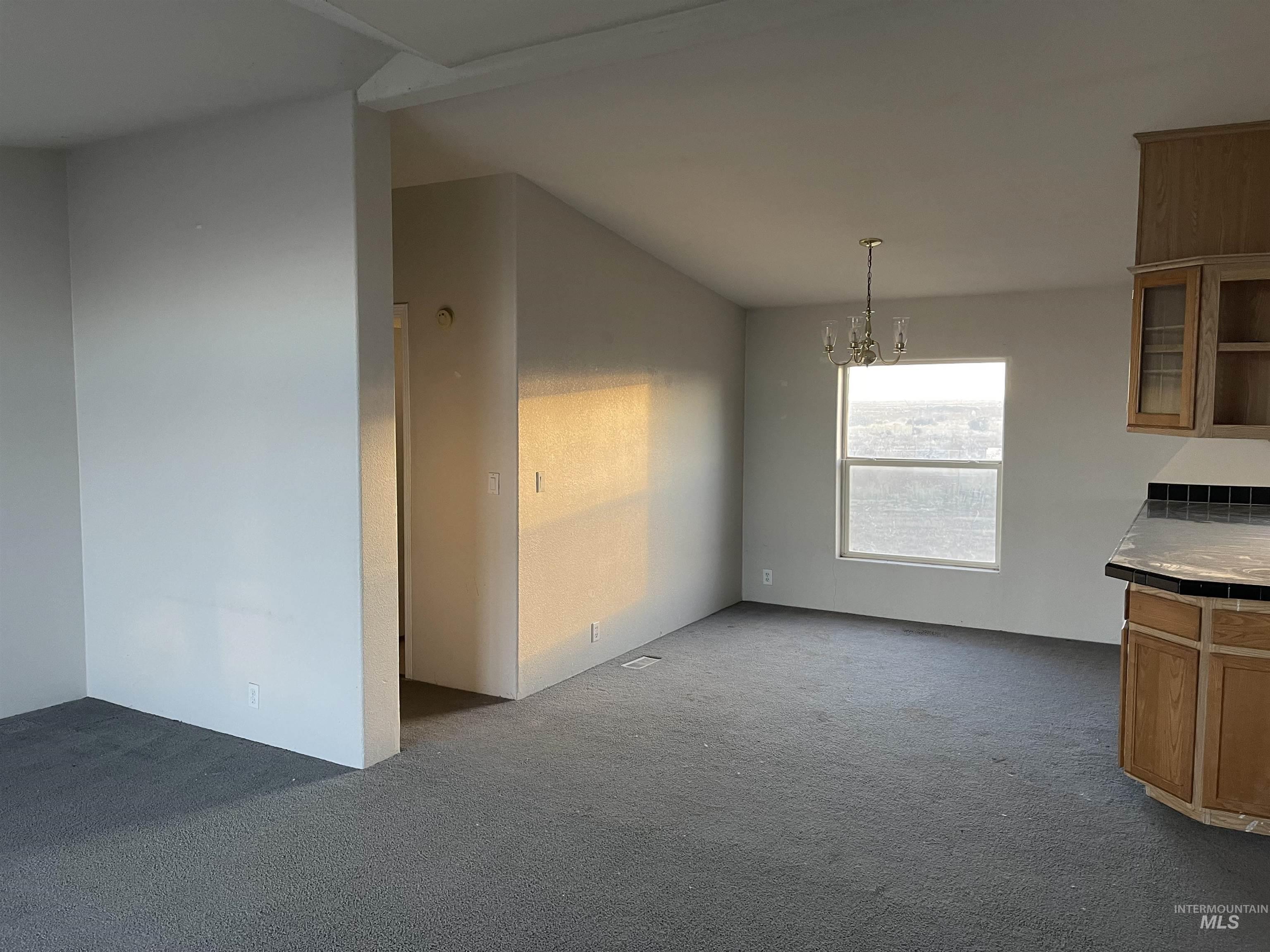 Unfurnished dining area with a chandelier and dark carpet
