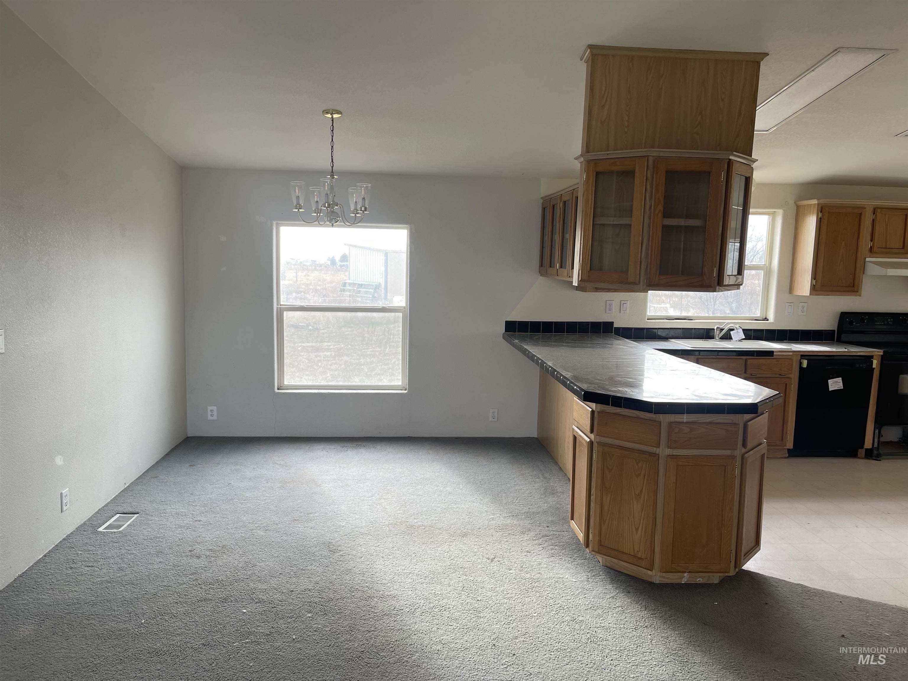 Kitchen with tile counters, a peninsula, black appliances, and plenty of natural light