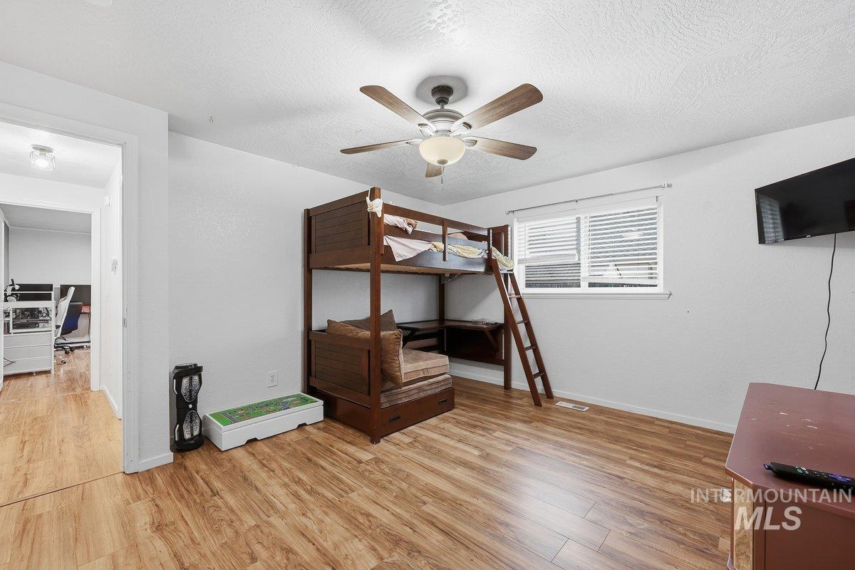 Unfurnished bedroom featuring light wood finished floors, a ceiling fan, and a textured ceiling