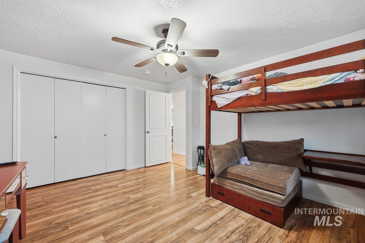 Bedroom with wood finished floors, a textured ceiling, ceiling fan, and a closet