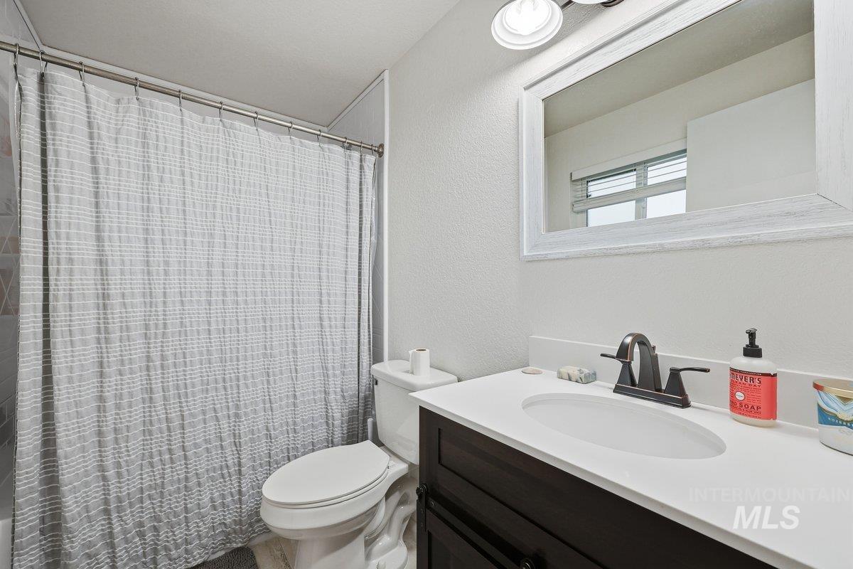 Bathroom featuring a textured wall, vanity, and curtained shower