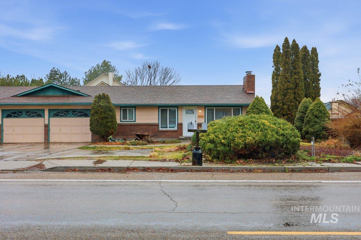 Ranch-style house featuring a chimney, concrete driveway, and an attached garage