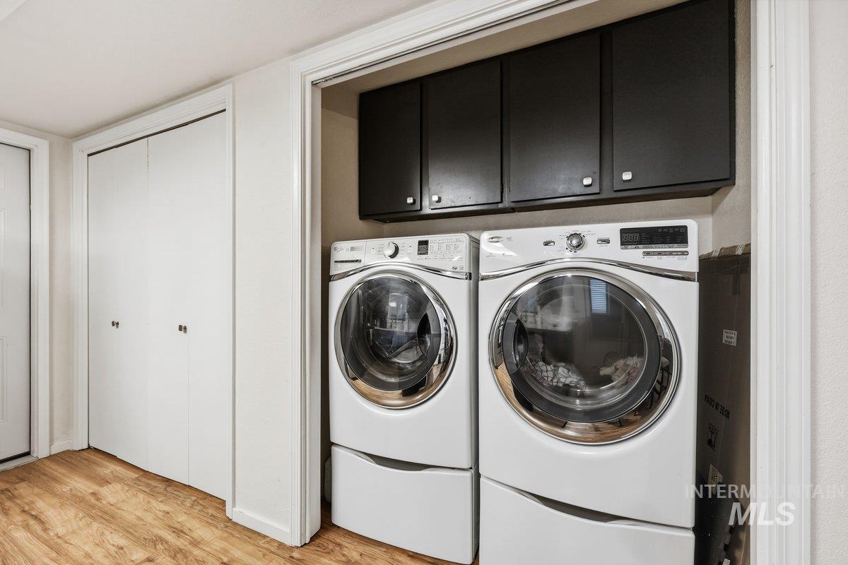 Washroom featuring cabinet space, light wood-style flooring, and independent washer and dryer