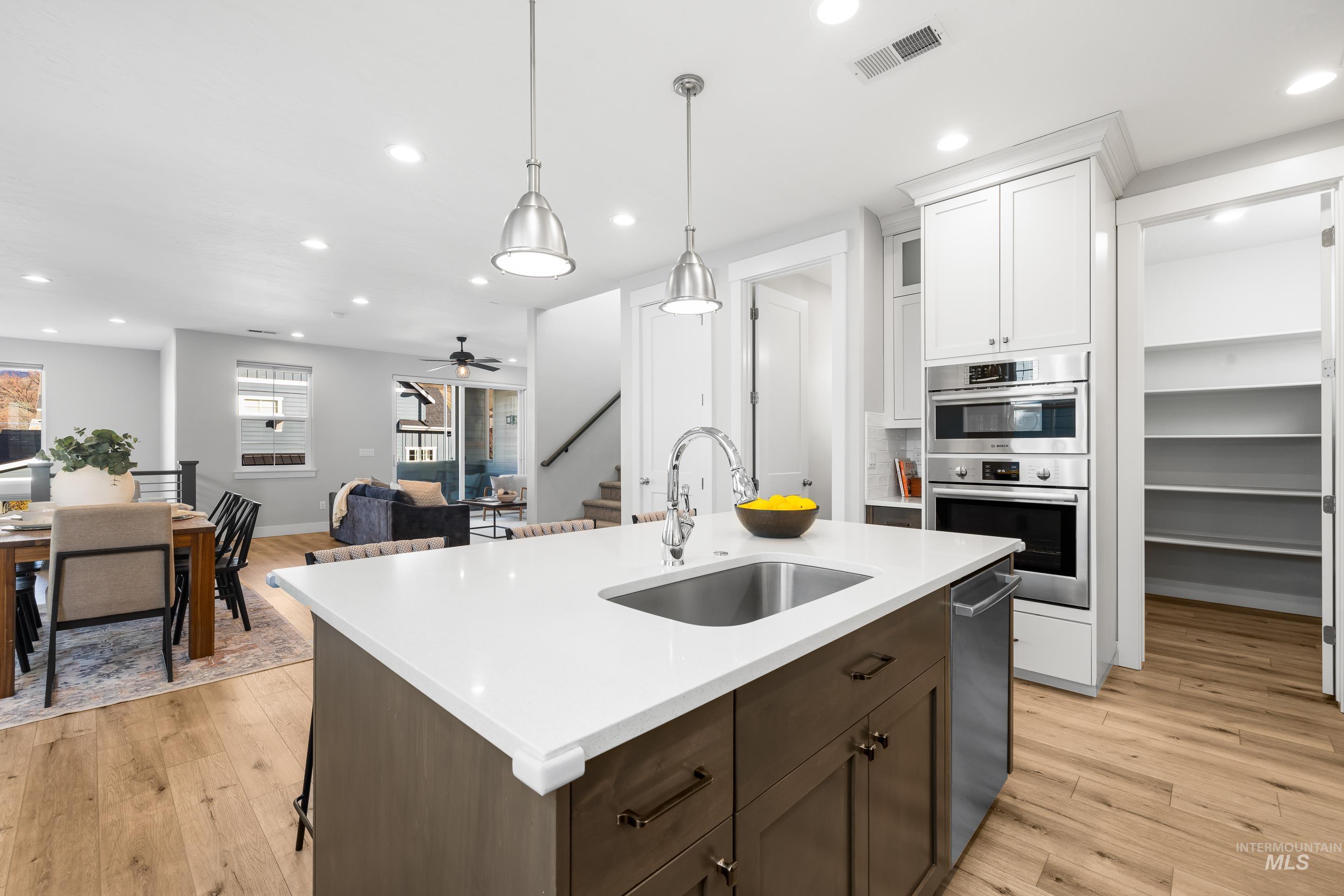 Kitchen with recessed lighting, dark brown cabinets, light wood-style flooring, white cabinetry, and open floor plan