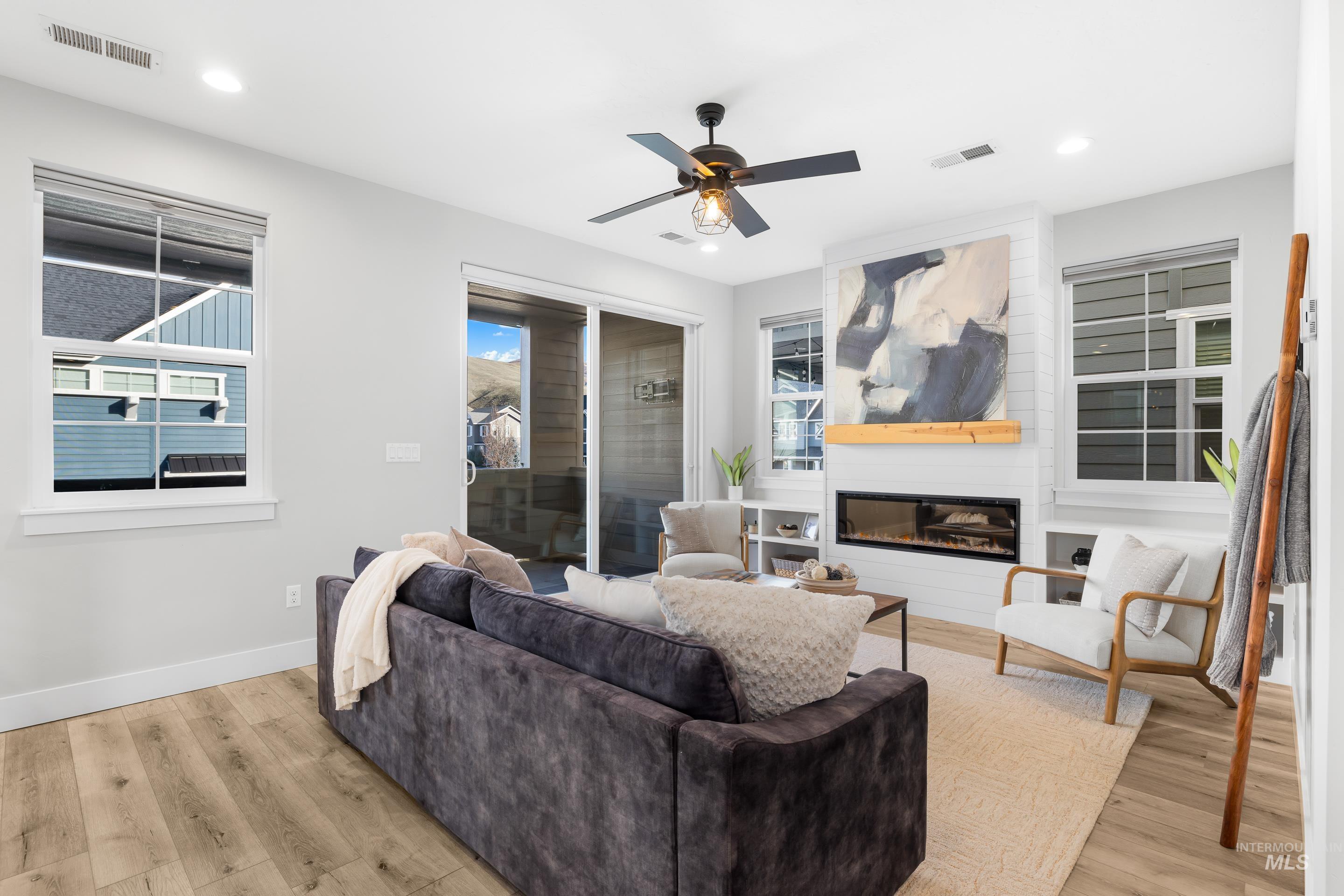 Living room with light wood-style flooring, a fireplace, ceiling fan, and recessed lighting