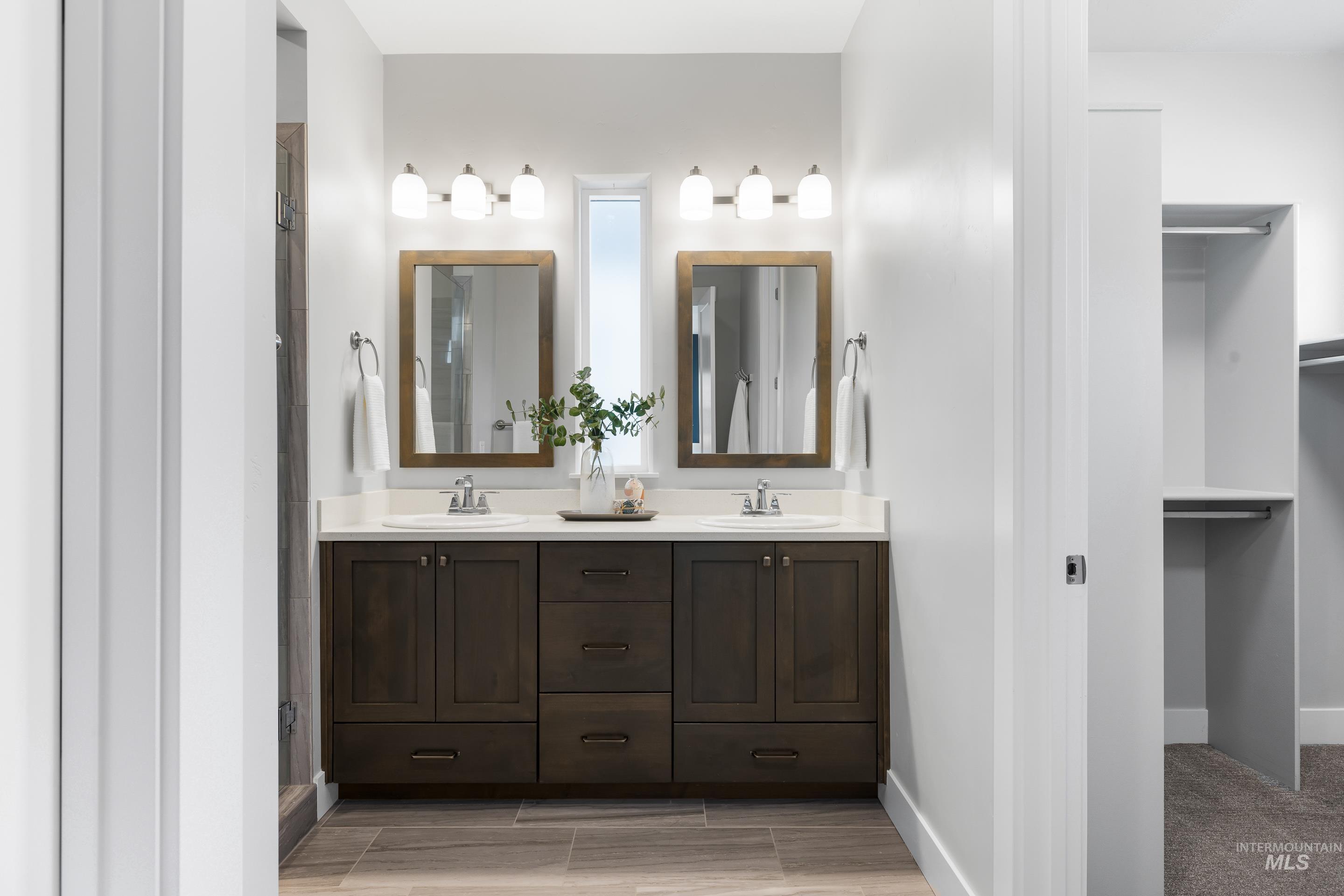Full bath with double vanity, a walk in closet, and a shower