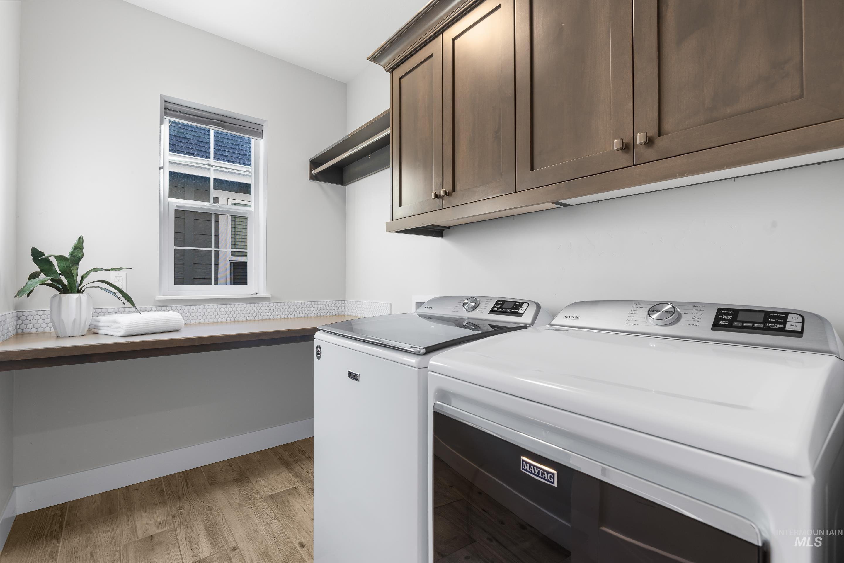 Laundry room with light wood-style flooring, washing machine and clothes dryer, and cabinet space