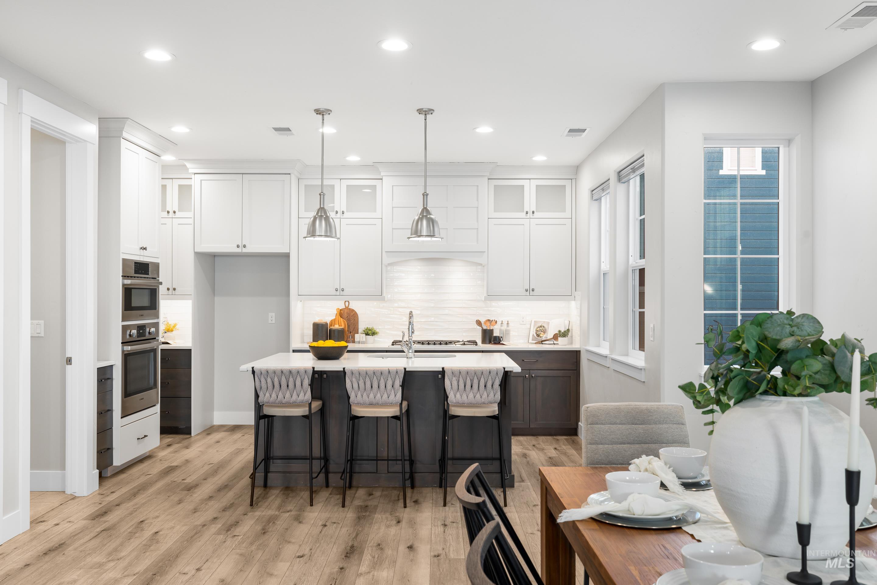 Kitchen featuring a breakfast bar, white cabinetry, glass insert cabinets, an island with sink, and recessed lighting