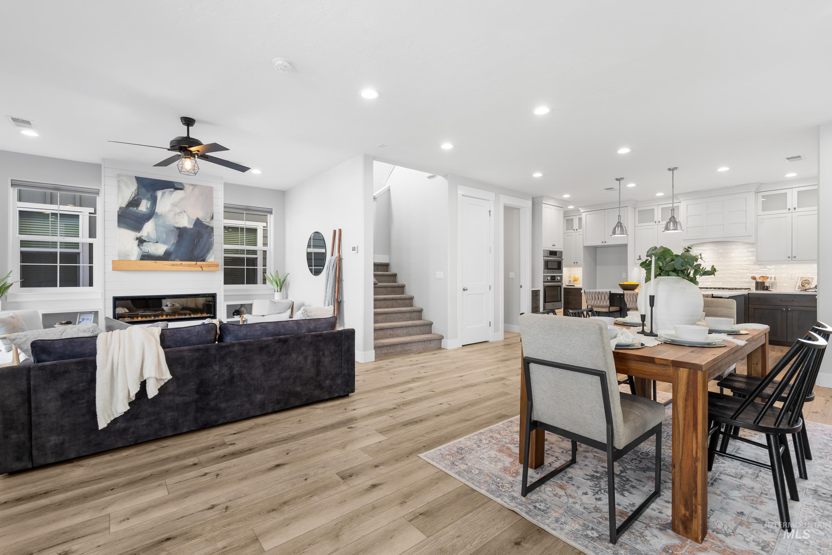 Dining space featuring recessed lighting, a large fireplace, light wood-type flooring, stairway, and a ceiling fan